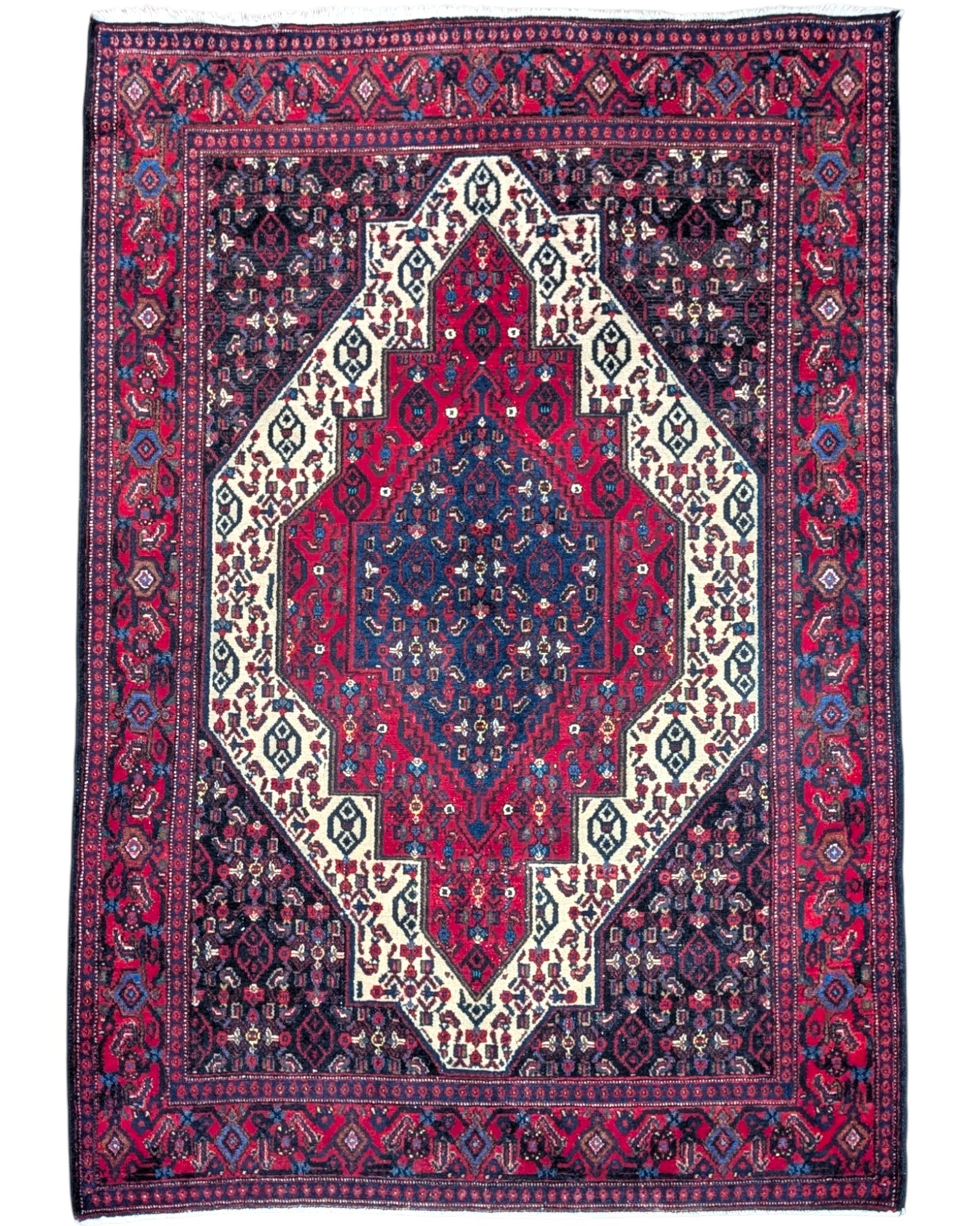 Tappeto Senneh 174x122 cm, annodato a mano, con grande medaglione geometrico centrale e motivi floreali su campo rosso e blu.