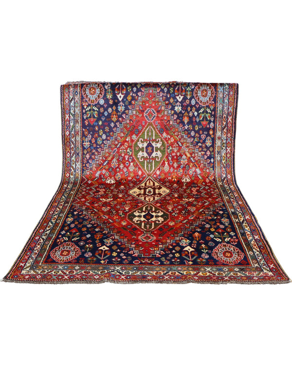 "Tappeto Ghashghai annodato a mano con motivi floreali e geometrici in blu, rosso, bianco, giallo e verde, 283x180 cm."