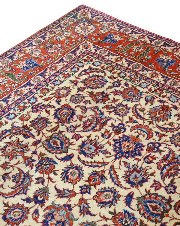 "Tappeto Esfahan annodato a mano con motivi floreali nei toni del blu, rosso, oro e verde su fondo avorio, 322x216 cm."