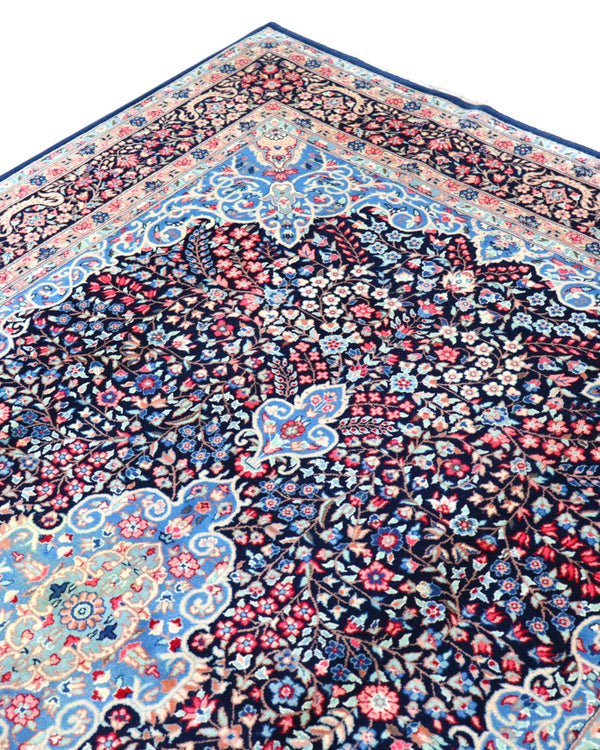 "Tappeto Kerman annodato a mano con motivi floreali in rosso, blu e avorio su fondo blu, 280x189 cm."