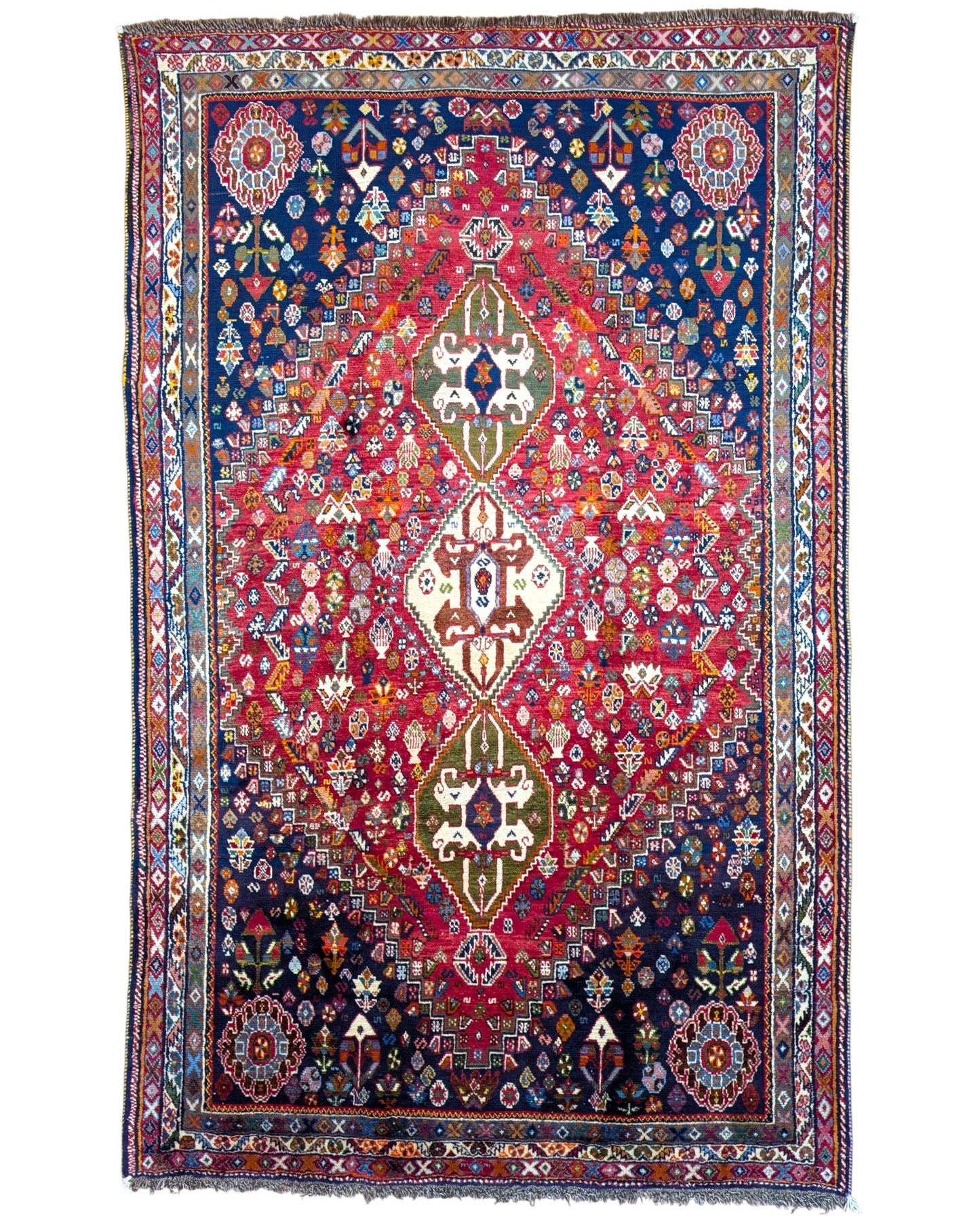 "Tappeto Ghashghai annodato a mano con motivi floreali e geometrici in blu, rosso, bianco, giallo e verde, 283x180 cm."