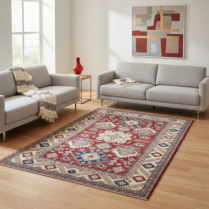 Tappeto Kazak 330x224 cm con fondo rosso, medaglione centrale avorio e motivi geometrici blu e azzurri, tramato ed annodato a mano, provenienza Caucaso.