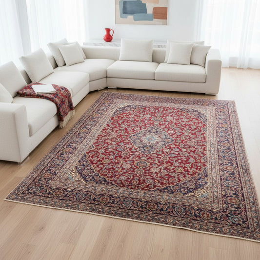 Tappeto persiano Mashhad 385x290 cm, fondo rosso con medaglione centrale e cornice floreale blu e beige, annodato a mano in lana vegetale.