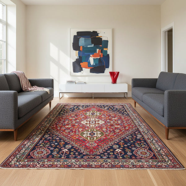 "Tappeto Ghashghai annodato a mano con motivi floreali e geometrici in blu, rosso, bianco, giallo e verde, 283x180 cm."