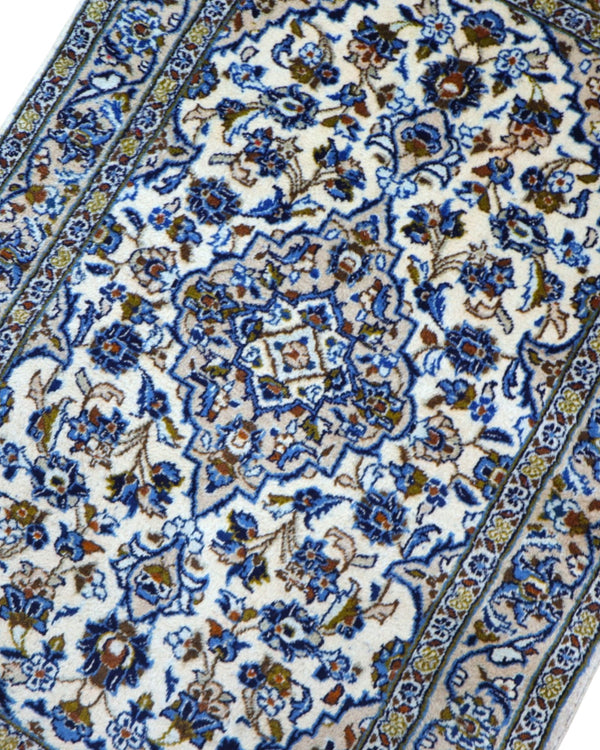 Tappeto Nain persiano 148x100 cm annodato a mano, fondo avorio con medaglione centrale e motivi floreali blu eleganti