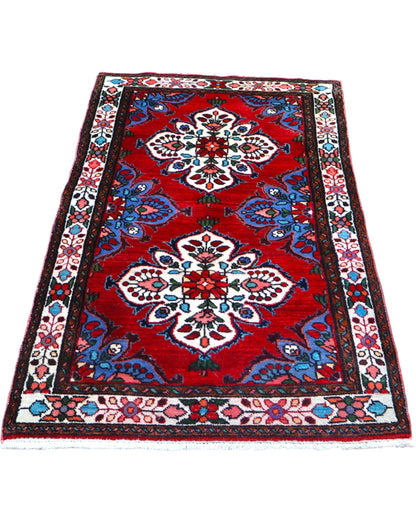 Tappeto Hamedan persiano 167x100 cm annodato a mano, fondo rosso con motivi floreali avorio e dettagli blu, design tradizionale con medaglioni simmetrici